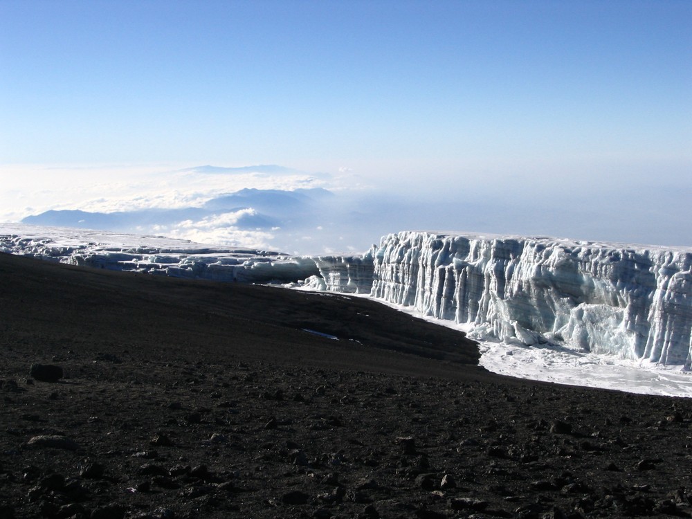 Pogled sa samog vrha na snegove Kilimanjara, sa druge strane, sa oboda kratera. Mislio sam da je sneg i na vrhu. Popeo sam Kilimanjaro a da nisam ugazio u sneg. Obične planinarske cipele kao za naše planine. Ovo su lednici, a ne snegovi. Na žalost mi ljudi ćemo i to uništiti. Mora da je ovde bilo prelepo pre 50god. Sada samo crna vulkanska šljaka na vrhu, kao koks, čvrsto, šupljikavo, bockavo. Poneo sam jednu kesu toga. Obično mi carinici nađu to kamenje i čude se šta to nosim - kamenje, svašta.